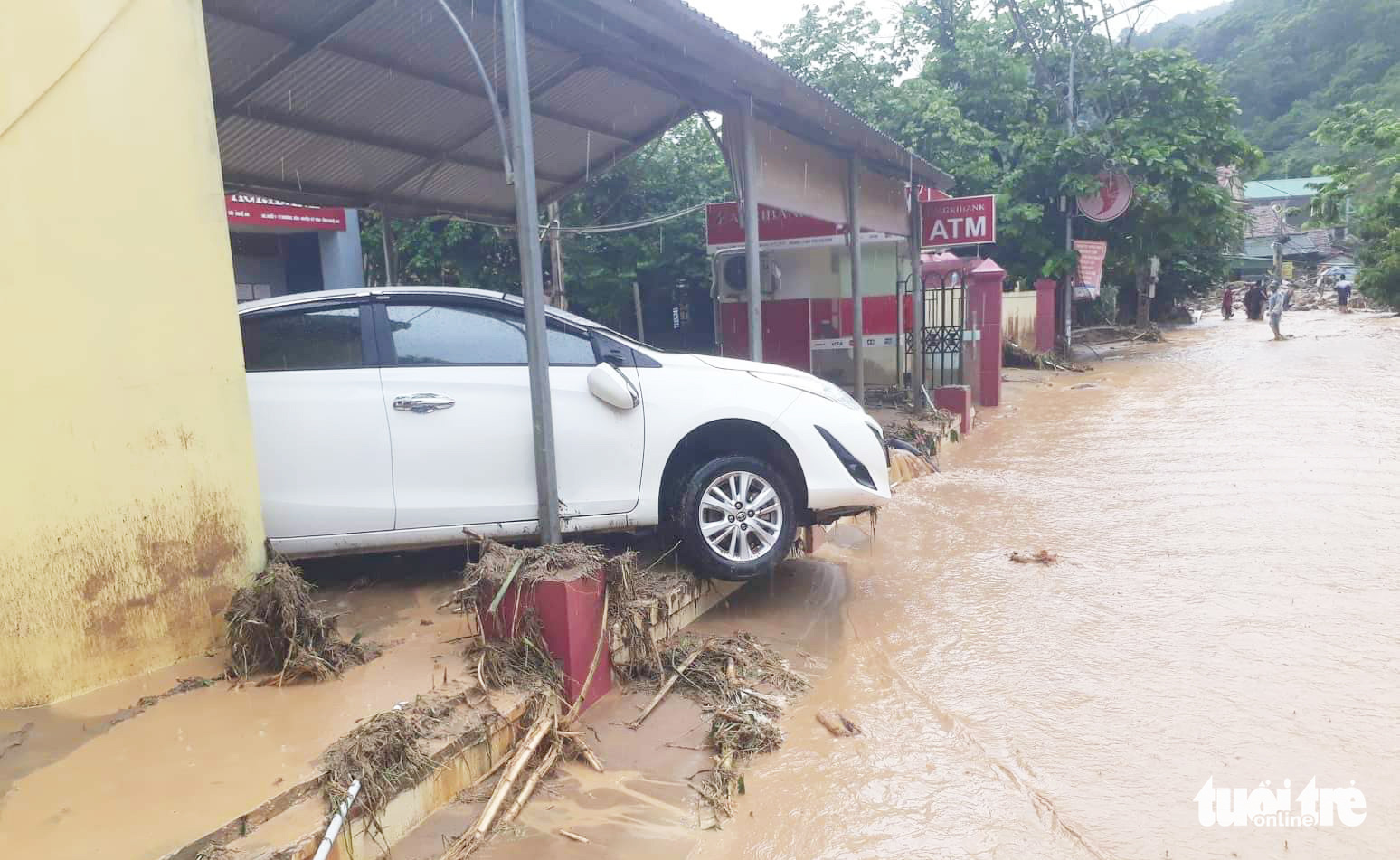 A car is washed away to a bank office following a flash flood in Ky Son District, Nghe An Province, Vietnam, October 2, 2022. Photo: N. Thang / Tuoi Tre
