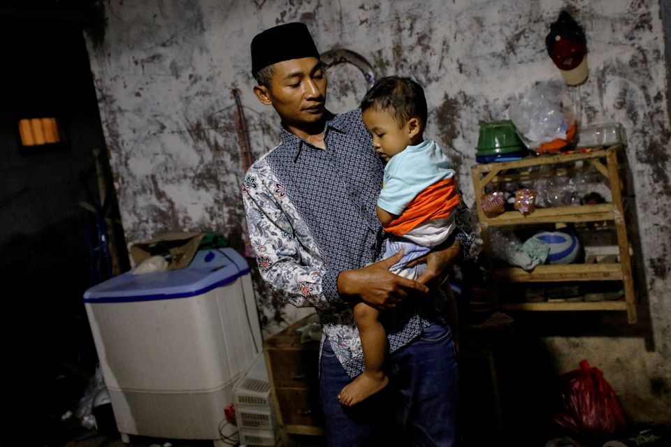 Andi Hariyanto, 36, a husband who lost his wife and two adopted children in a recent riot and stampede following a soccer match between Arema FC and Persebaya Surabaya at Kanjuruhan stadium, carries his 2-year-old son Gean Putra Hariyanto, at his house in Malang, East Java province, Indonesia, October 4, 2022. Photo: Reuters
