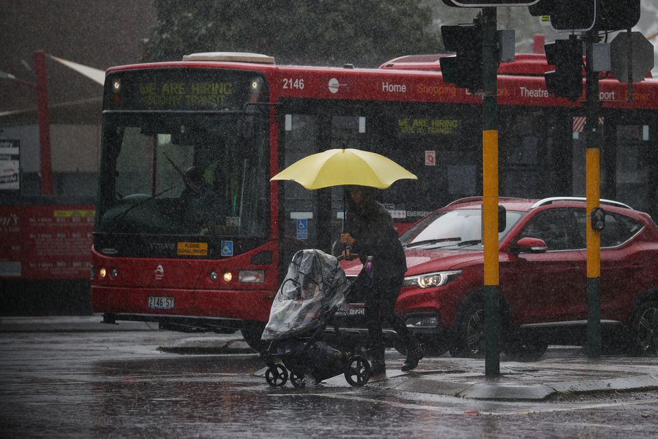 A pedestrian pushing a baby pram crosses a flooding intersection as heavy rains affect Sydney, Australia, October 6, 2022. Photo: Reuters