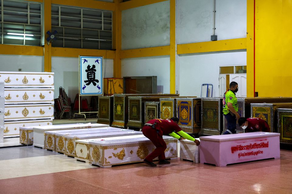 Rescue workers arrange coffins containing the body of victims at Song Serm Tham Foundation after transfer from Udon Thani hospital in Udon Thani province, following a mass shooting in the town of Uthai Sawan, around 500 km northeast of Bangkok in the province of Nong Bua Lam Phu, Thailand October 7, 2022. Photo: Reuters