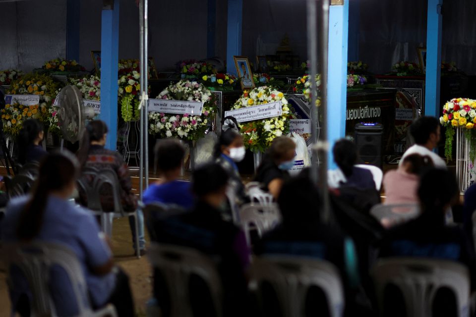 Relatives sit nearby the coffins of victims at Sri Uthai temple in Na Klang district, following a mass shooting in the town of Uthai Sawan in the province of Nong Bua Lam Phu, Thailand October 7, 2022. Photo: Reuters