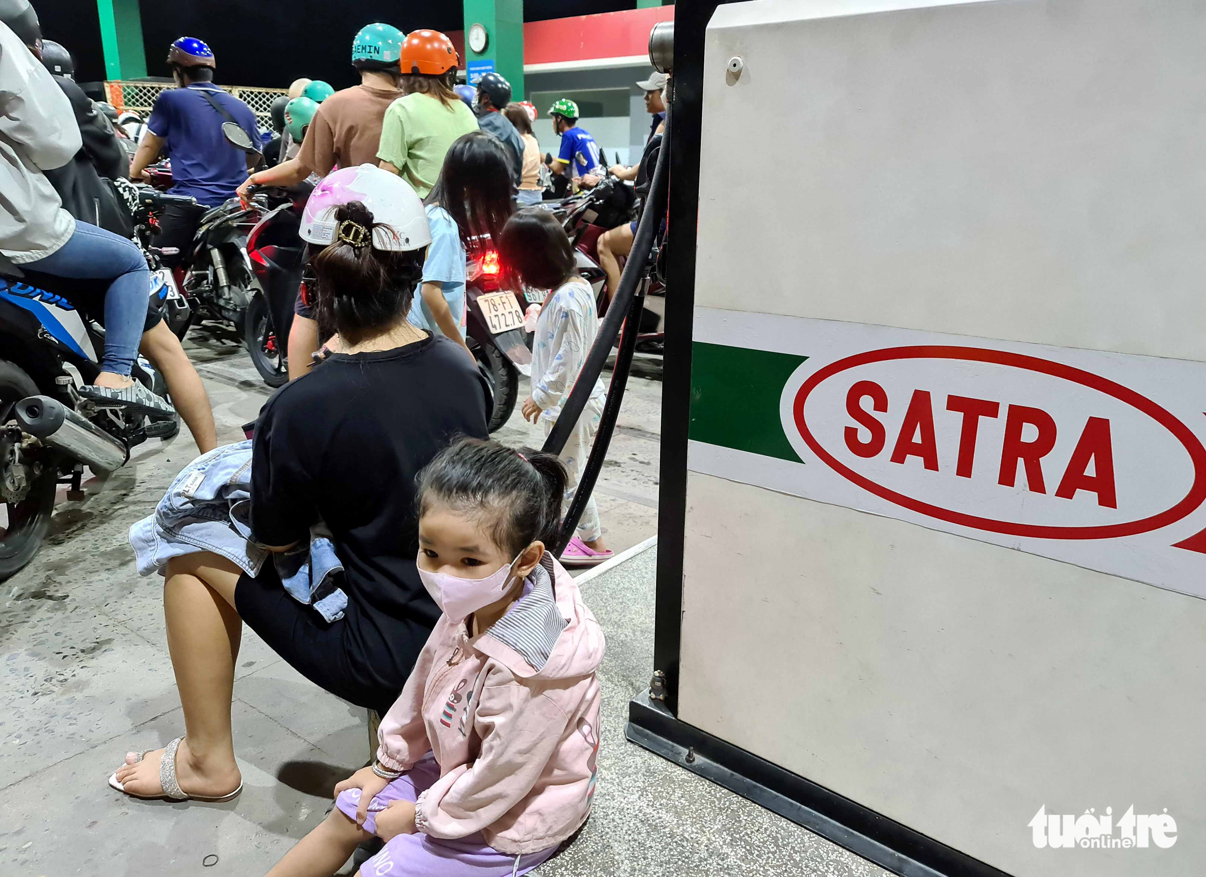 A kid waits for her parents at a crowded filling station in District 12, Ho Chi Minh City, October 9, 2022. Photo: Ngoc Hien / Tuoi Tre