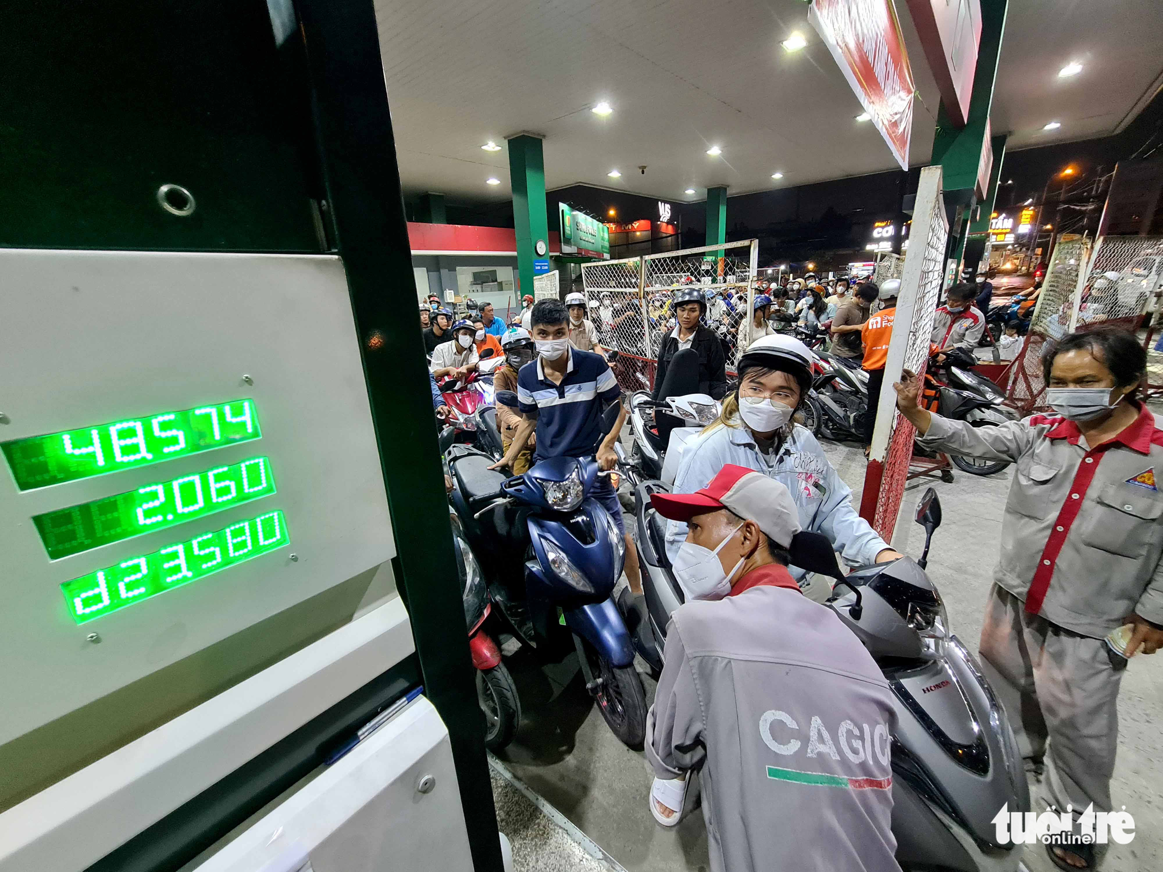 An employee refills a woman's motorbike while his colleague holds a fence to prevent hustling at a filling station in District 12, Ho Chi Minh City, October 9, 2022. Photo: Ngoc Hien / Tuoi Tre
