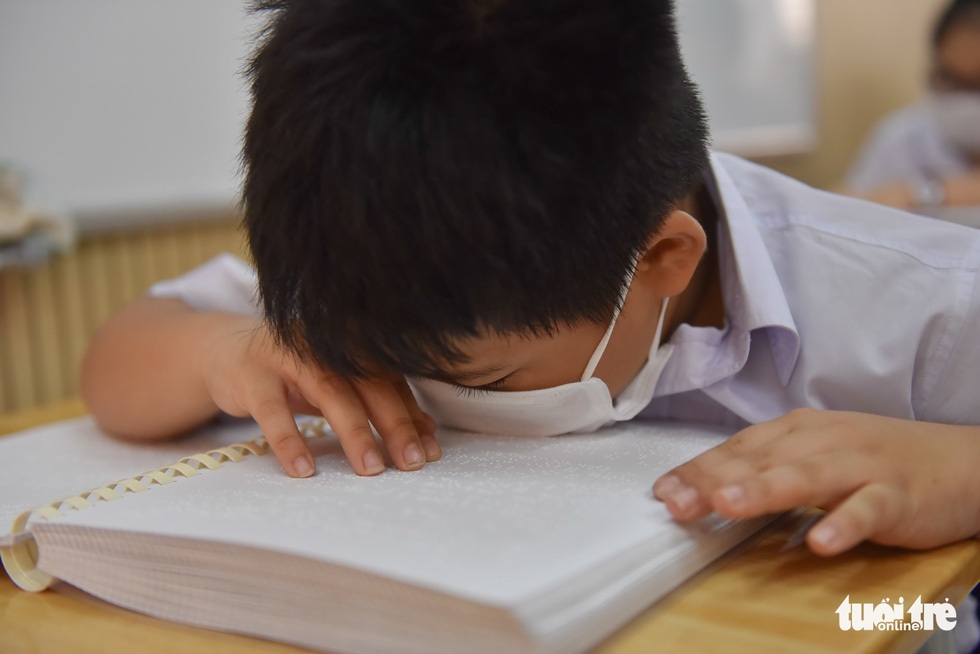 Nguyen Huynh Vu Duy, a grade 3 student, reads a new Braille book made by his teachers. Photo: Ngoc Phuong - Pho Huong