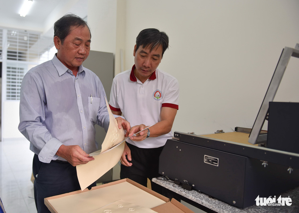 Teachers Phi Hung (left) and Dinh Hau engage with book pages with Braille characters. Photo: Ngoc Phuong - Pho Huong