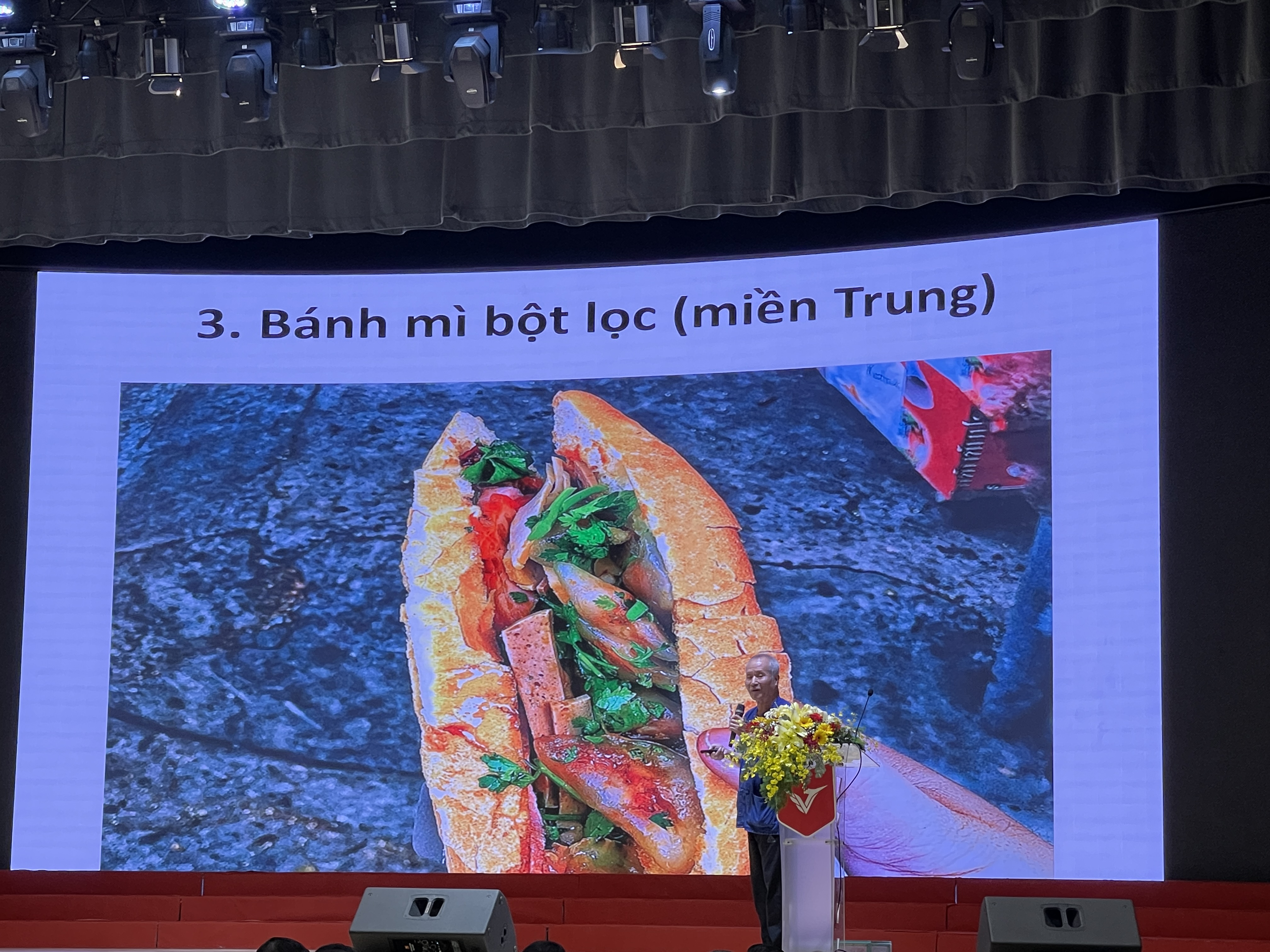 Historian Vu The Long speaks at the conference on the background photo of a ‘banh mi bot loc’ (banh mi stuffed with Vietnamese tapioca dumplings) which can be found in the central region of Vietnam. Photo: Photo: Dong Nguyen / Tuoi Tre News