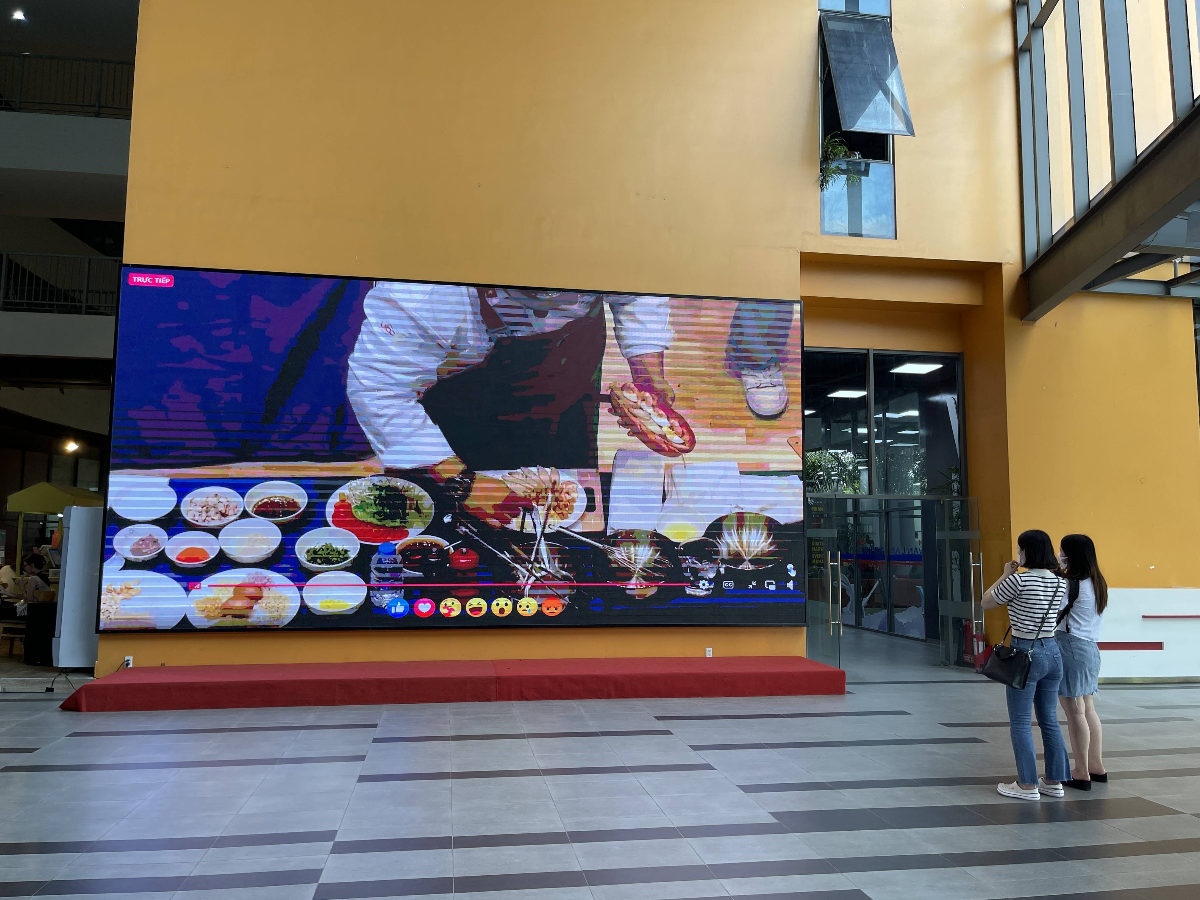 Two students watch Singaporean chef Eric Low making a Laksa and chill crab banh mi through a live screen on the campus of Van lang University in Ho Chi Minh City on October 11, 2022. Photo: Dong Nguyen / Tuoi Tre News