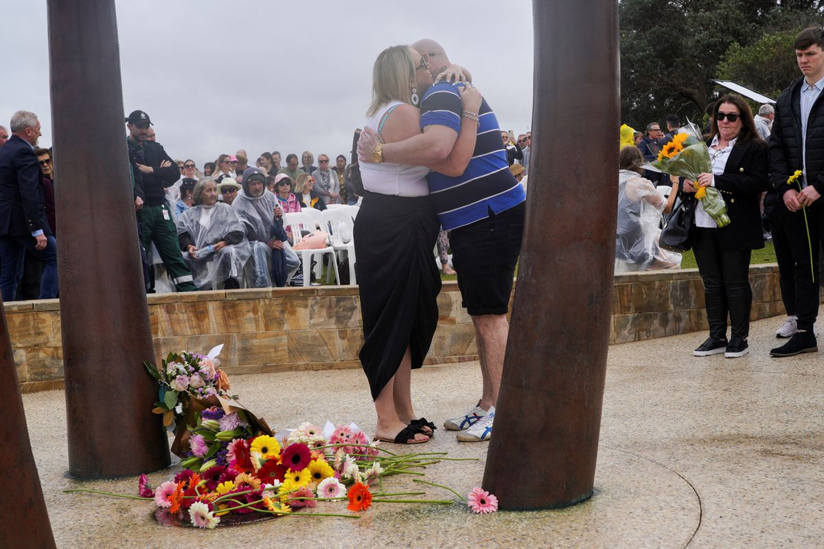 Mourners hug while taking part in a flower laying ceremony during a memorial service to mark the 20th anniversary of the Bali bombings, which killed 202 people including 88 Australians, at Coogee Beach in Sydney, Australia, October 12, 2022. REUTERS/Loren Elliott