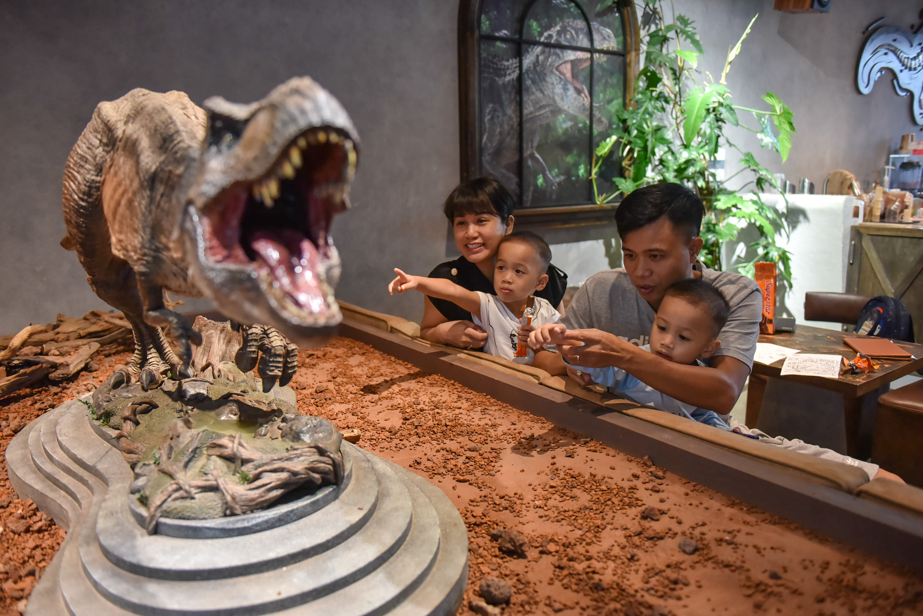Nguyen Huu Loi and his family look at dinosaur models on display at SAURUS Coffee & Gallery in Go Vap District, Ho Chi Minh City. Photo: Ngoc Phuong / Tuoi Tre News