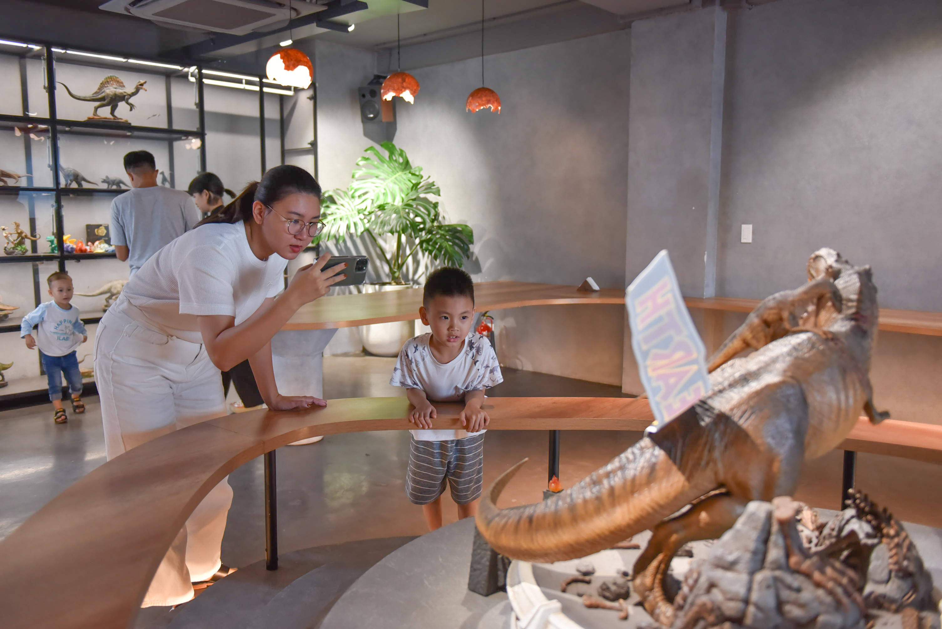 A woman takes a picture of a dinosaur model on display at SAURUS Coffee & Gallery in Go Vap District, Ho Chi Minh City. Photo: Ngoc Phuong / Tuoi Tre News