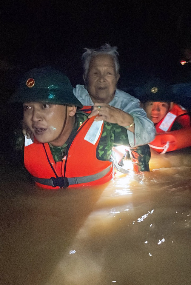 This supplied photo shows rescuers taking an elderly woman through floodwaters to safety in Lien Chieu District, Da Nang City, October 14, 2022.