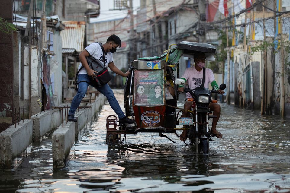 A man steps in a motorcycle taxi, modified to cope with flooding, in the coastal town of Hagonoy, Bulacan province, Philippines, September 23, 2022. Photo: Reuters