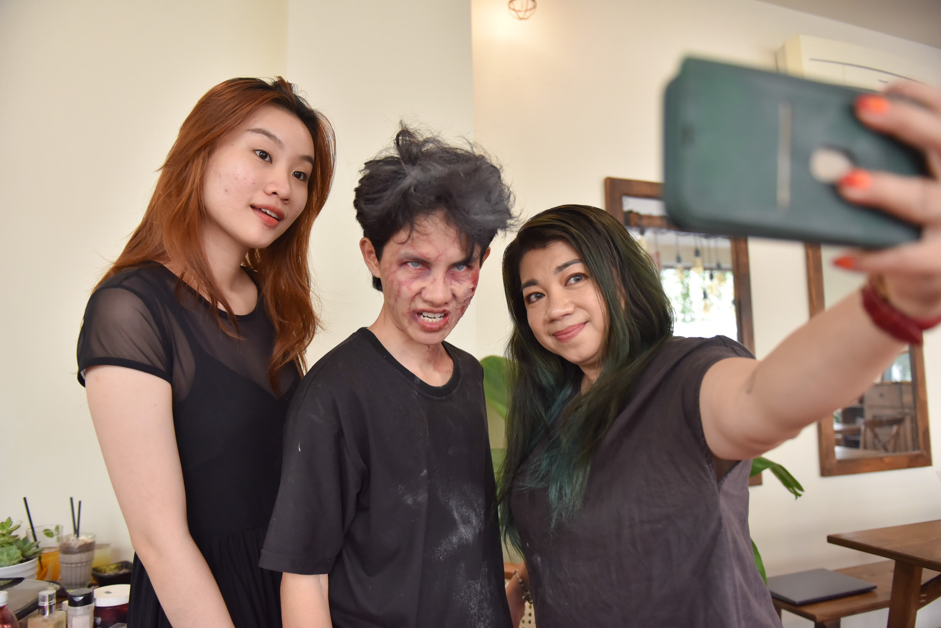 Hang (right) poses for a selfie with actor Ngoc Tuan (center) after she turns him into a zombie with her makeup techniques. Photo: Ngoc Phuong / Tuoi Tre News