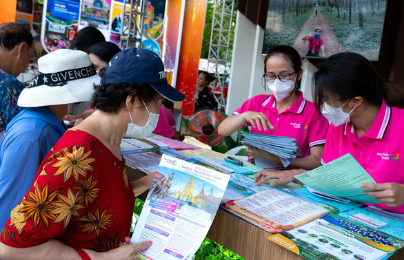 A photo shows customers considering selecting discounted tours at the 2022 Ho Chi Minh City Travel Expo. Photo: Huu Hanh / Tuoi Tre