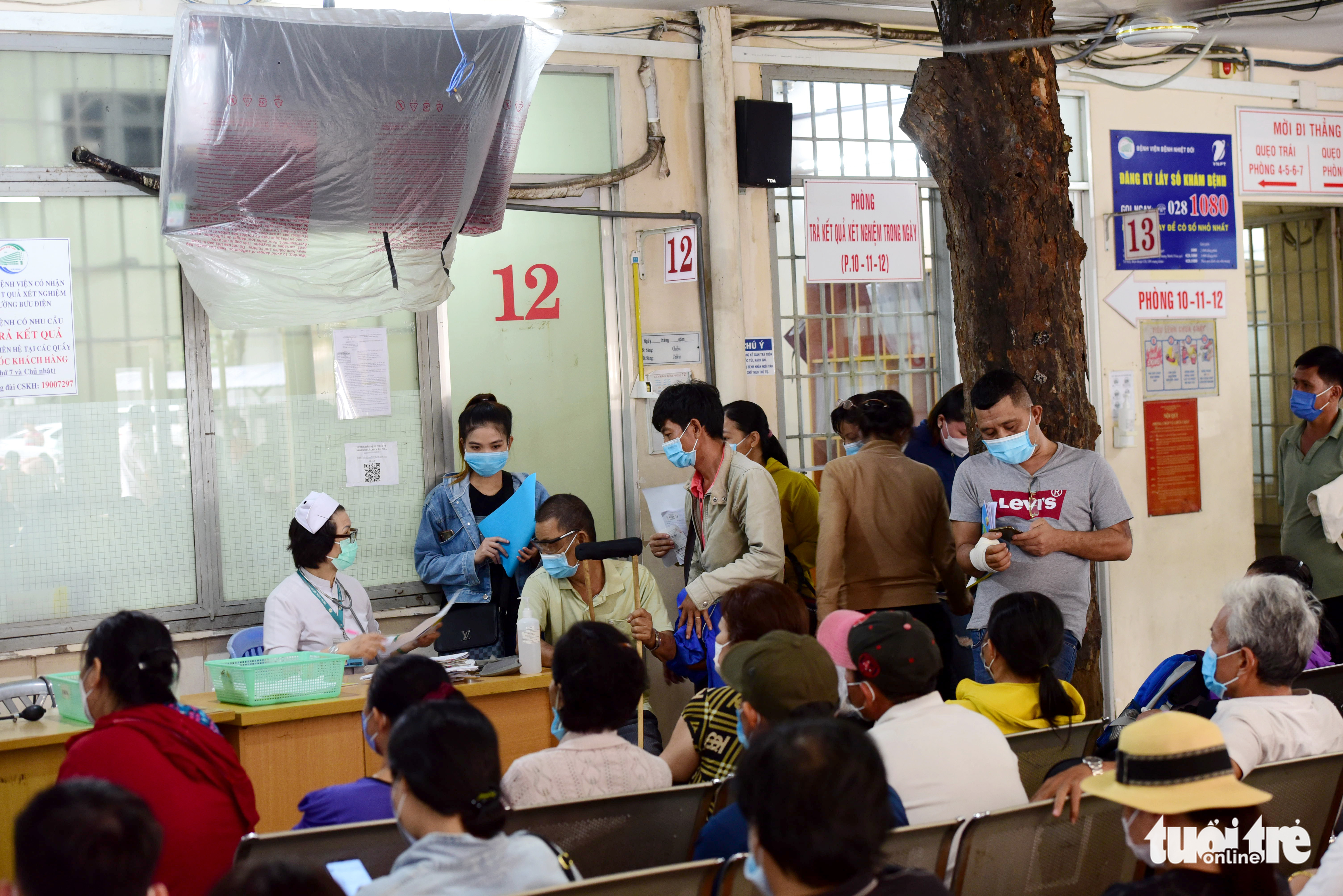 Patients wait for health checks at a prefabricated space, where a tree still remains, at the Ho Chi Minh City Hospital for Tropical Diseases. Photo: Duyen Phan / Tuoi Tre