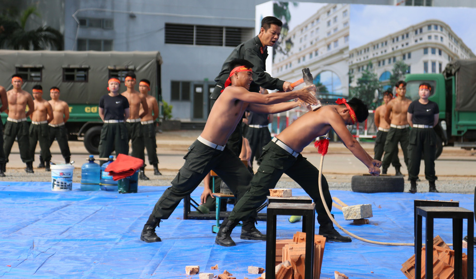 An officer uses a hammer to break a brick on the back of another officer. Photo: Minh Hoa / Tuoi Tre