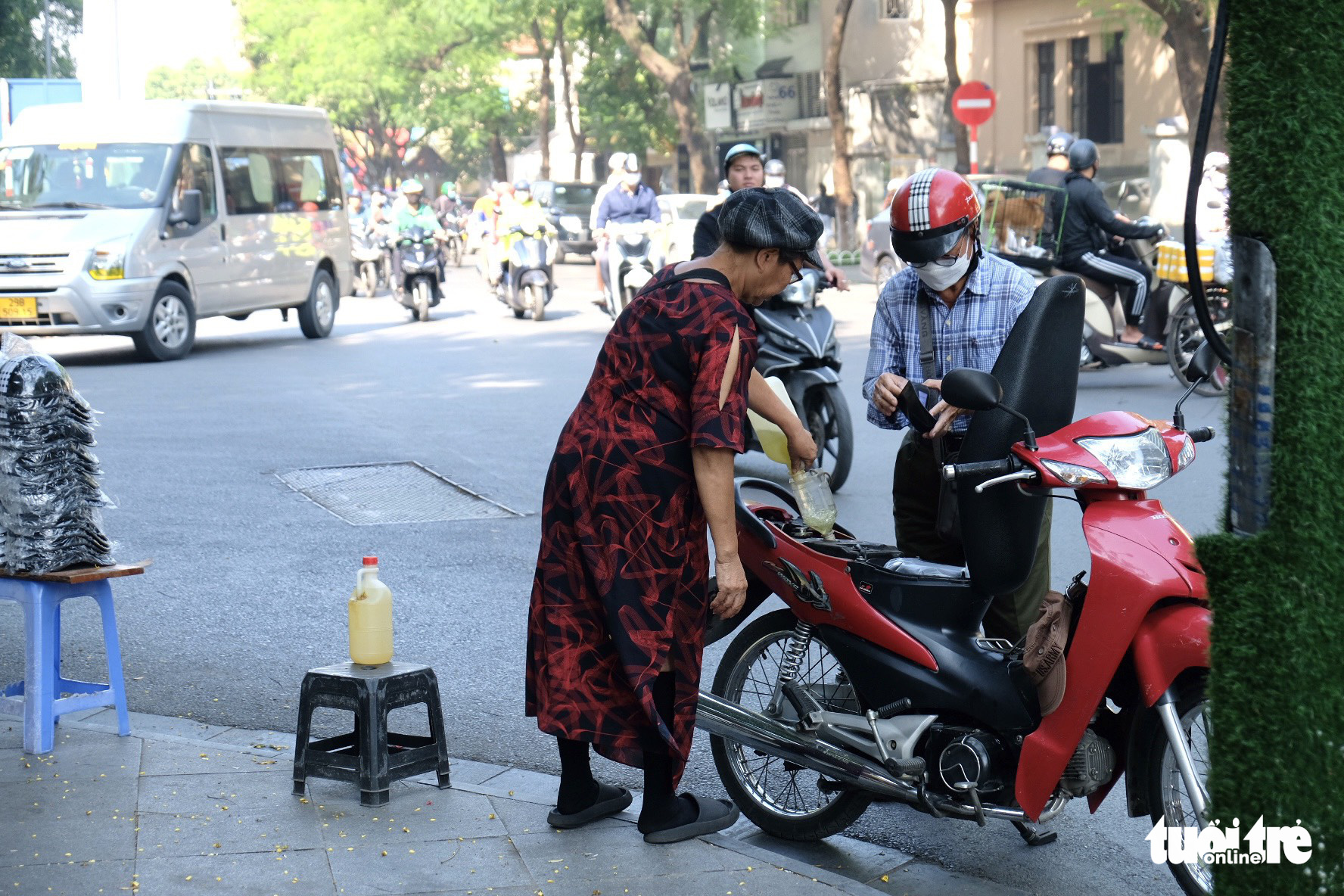 A street vendor pours a bottle of two liters of gasoline into a man’s motorbike tank for VND60,000 (US$2.41) on a street in Hanoi, November 3, 2022. Photo: Nguyen Bao / Tuoi Tre