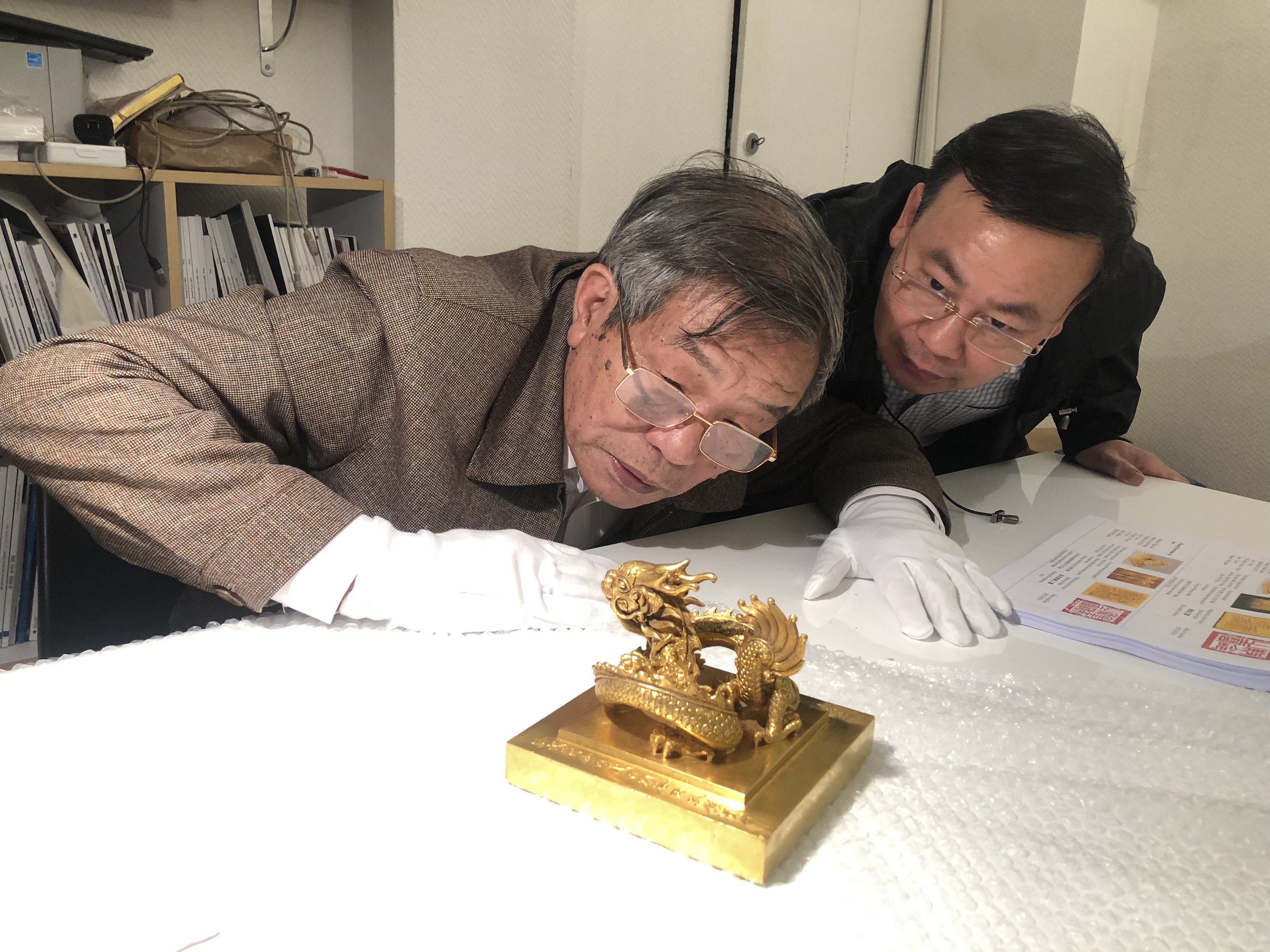 Officials evaluate the gold seal at auction house Millon’s office in Paris, France. Photo: Department of Cultural Heritage