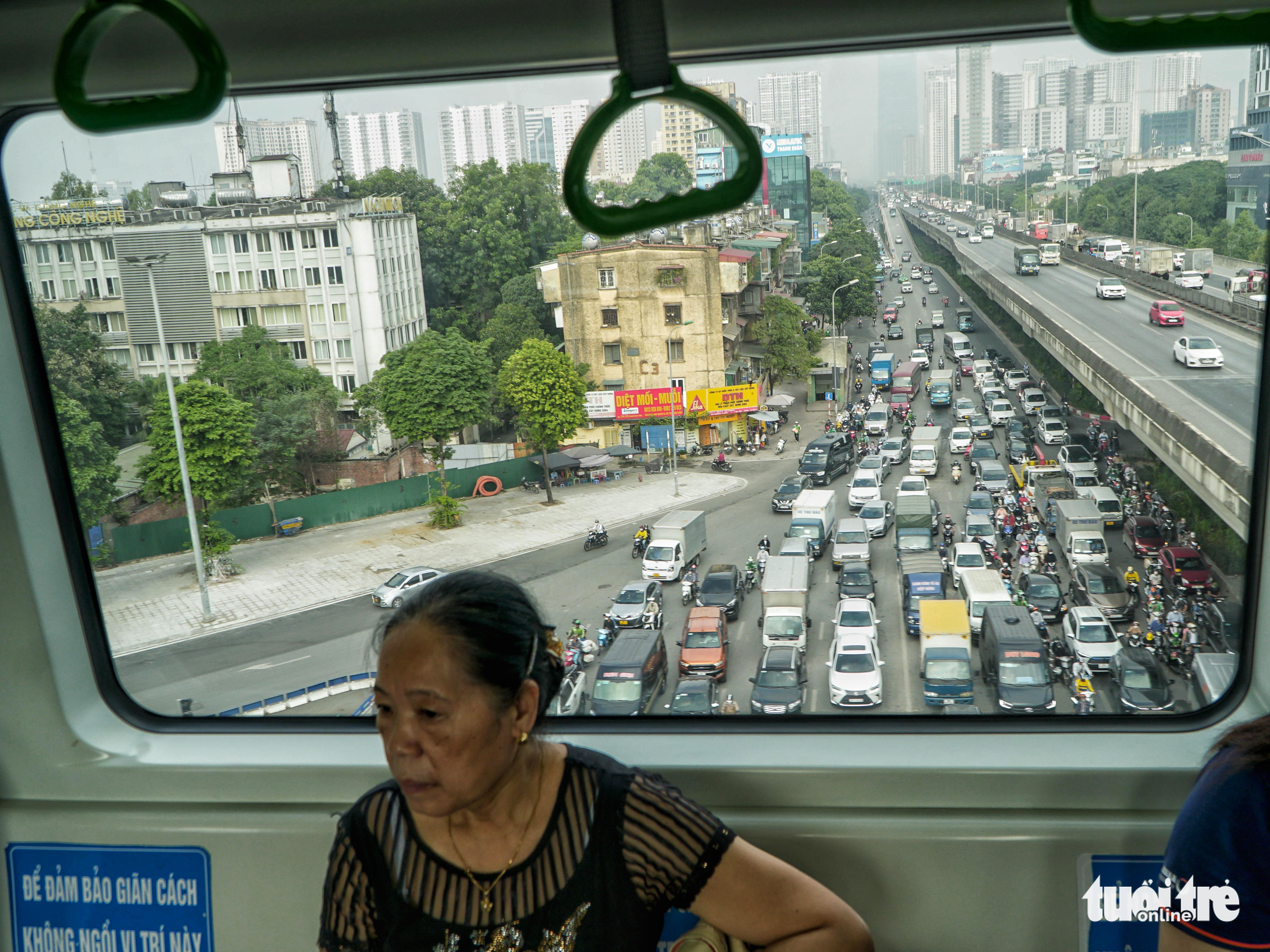 A woman boards the Cat Linh-Ha Dong metro line while automobiles queue on a road below the elevated route in Hanoi, November 16, 2022. Photo: Pham Tuan / Tuoi Tre