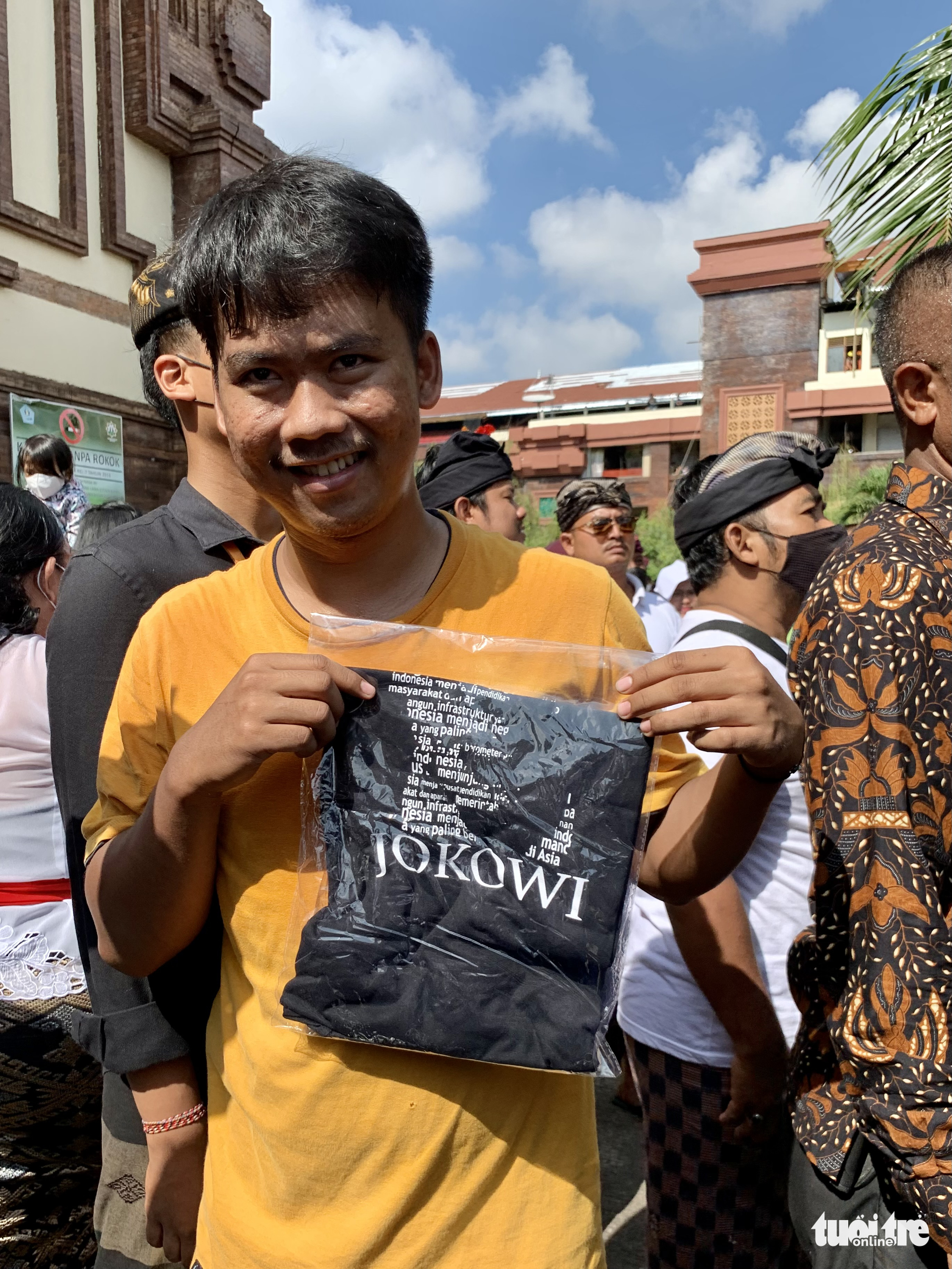 A resident receives a black T-shirt given out by Indonesian President Joko Widodo during the leader's inspection tour at Badung traditional market in Bali, Indonesia, November 17, 2022. Photo: Duy Linh / Tuoi Tre