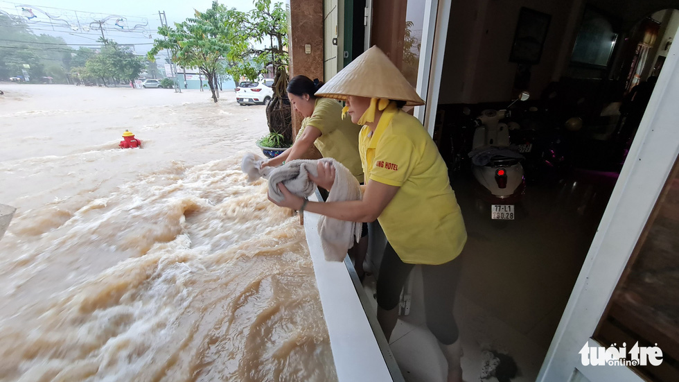 Local residents use a plank to shield their house from floodwater. Photo: Lam Thien / Tuoi Tre