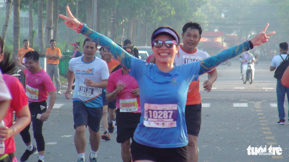 A female runner gives a bright smile to the spectators.