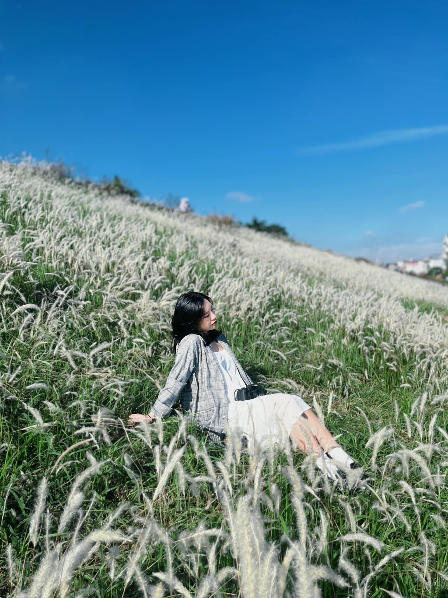 A woman poses for pictures at a white reed field on the embankment along the Red River section in Long Bien District, Hanoi, November 28, 2022. Photo: Huong Nguyen / Tuoi Tre