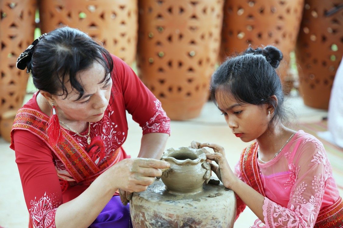 Children learn to make pottery in the village of Bau Truc in a photo of the panel preparing the documents on Cham pottery.