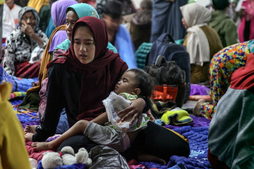 A woman holds a child as they shelter at a district office after being evacuated following the eruption of Mount Semeru volcano in Lumajang, East Java province, Indonesia, December 4, 2022, in this photo taken by Antara Foto. Photo: Antara Foto/Umarul Faruq/ via REUTERS