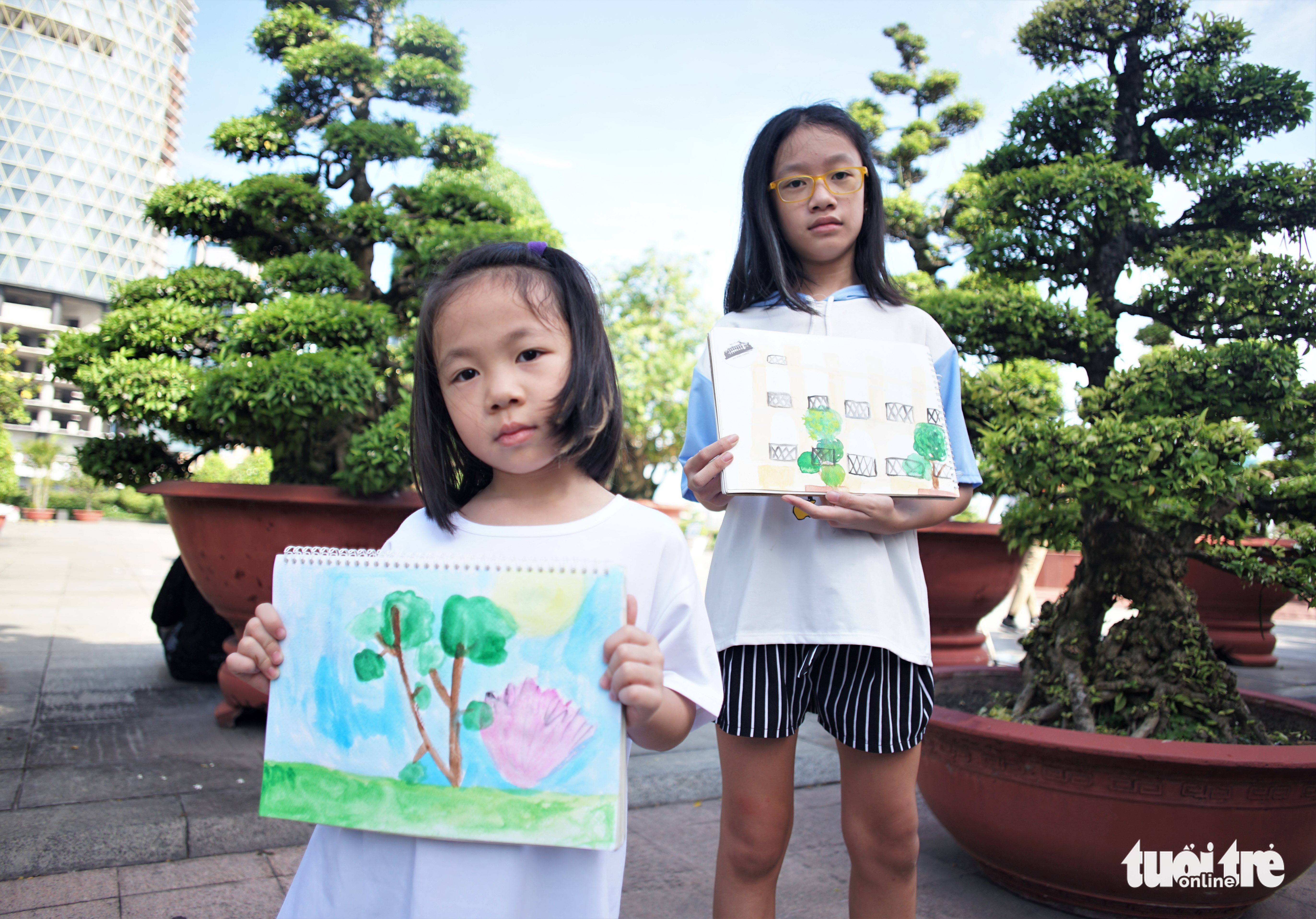 La La, 5, and Lam Anh, 9, two members of Urban Sketchers Vietnam, show their sketches. Photo: Huynh Vy / Tuoi Tre
