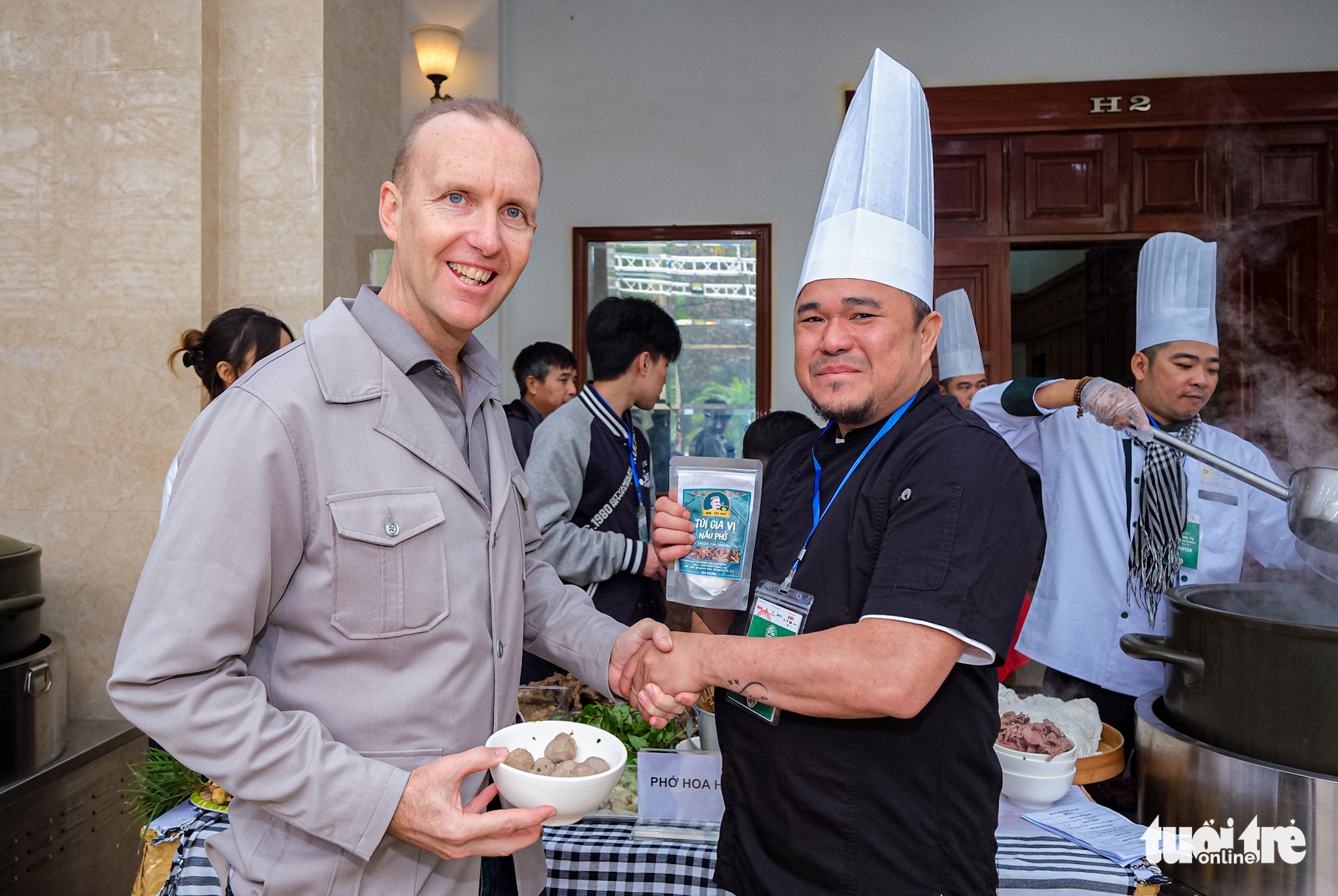 Warrant Officer Class Two Mark Phillips (L) of the Australian Embassy in Vietnam shakes hand with Cao Van Luan, winner of the 2019 Golden Star Anise award, at the Day of Pho event organized by Tuoi Tre (Youth) newspaper in Nam Dinh Province, Vietnam, December 10, 2022. Photo: Nam Tran / Tuoi Tre