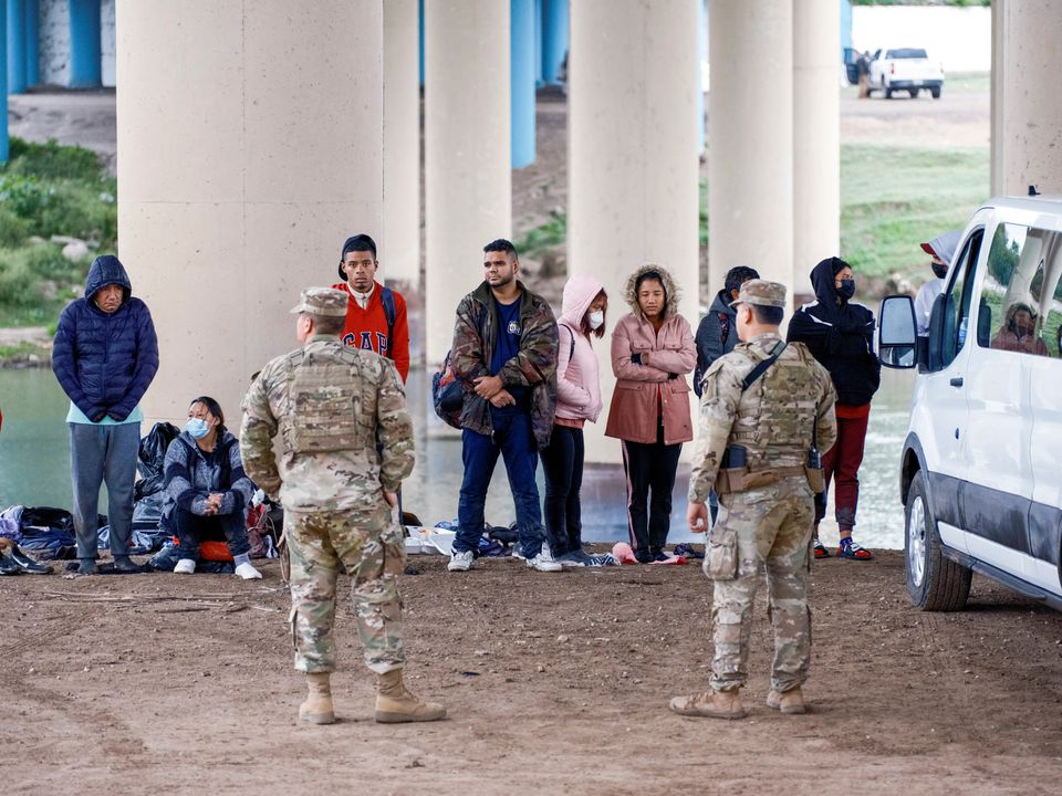A group of migrants is processed by Texas National Guard after crossing the Rio Grande as U.S. border cities are bracing for an influx of asylum seekers when COVID-19-era Title 42 migration restrictions are set to end, in Eagle Pass, Texas, U.S. December 19, 2022. Photo: Reuters