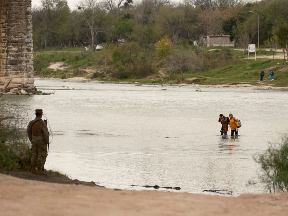 A Texas National Guardsman watches as a group of migrants wades across the Rio Grande as U.S. border cities brace for an influx of asylum seekers when COVID-era Title 42 migration restrictions are set to end, in Eagle Pass, Texas, U.S. December 18, 2022. Photo: Reuters