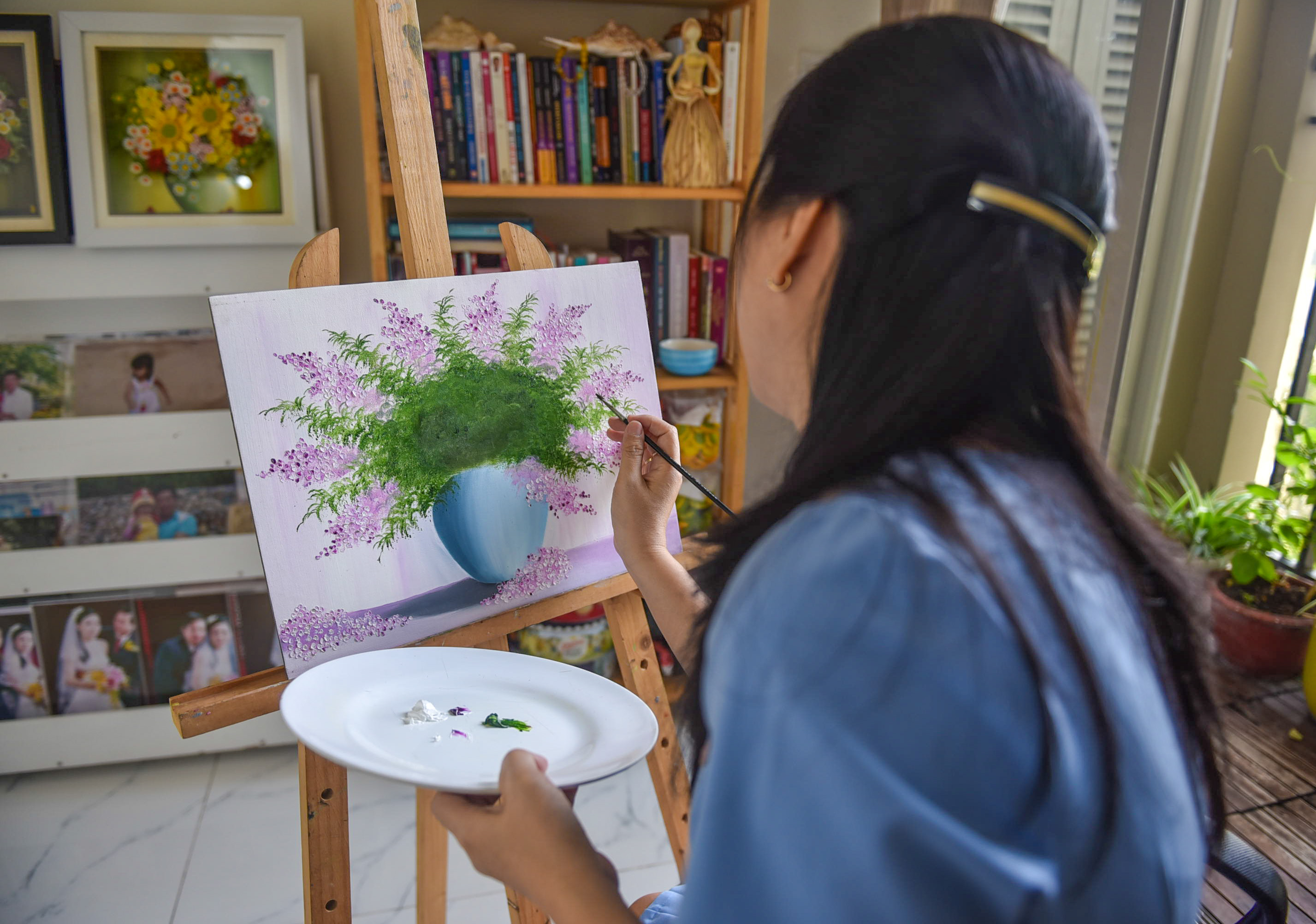 Pham Thi Giang Sinh paints a vase of flowers before attaching clay flowers to the piece. Photo: Ngoc Phuong / Tuoi Tre News