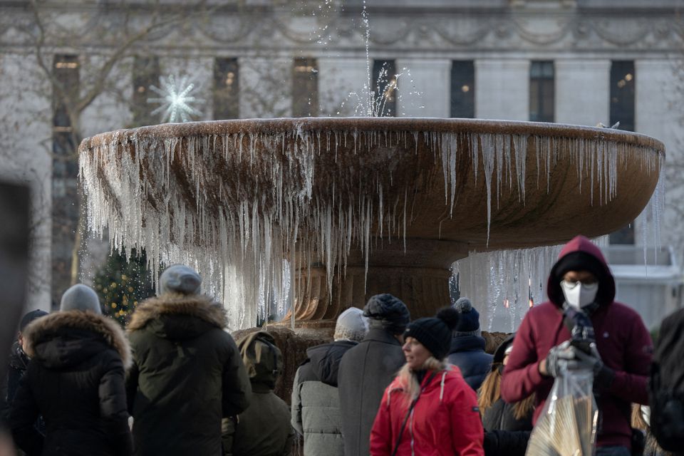 People stand in front of a mostly frozen Bryant Park fountain on Christmas Eve in Manhattan on Christmas Eve in Manhattan, New York City, U.S., December 24, 2022. Photo: REUTERS