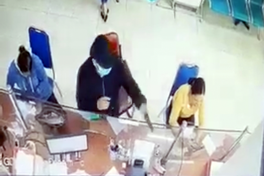 A screenshot taken from CCTV footage showing Tu Thanh Tung pointing a gun-shaped object at a woman at a bank in Dong Nai Province, Vietnam. December 28, 2022.