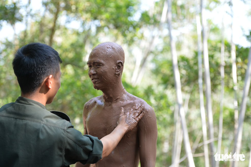 A trainee covers his body with mud during a camouflage training session. Photo: Danh Trong / Tuoi Tre