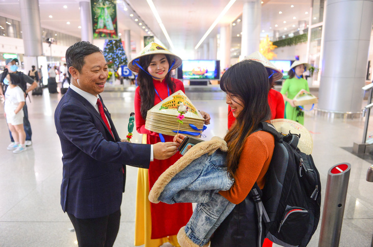Ho Chi Minh City Vice Chairman Duong Anh Duc gives to he (toy figurines) to Kieu Anh, a tourist flying from Germany to Ho Chi Minh City on the morning of January 1, 2023. Photo: Quang Dinh / Tuoi Tre