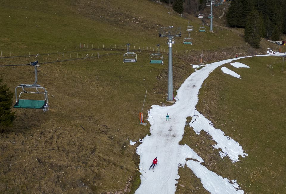 Skiers pass on a small layer of artificial snow amid warmer-than-usual winter temperatures in the Alps in Leysin, Switzerland, January 4, 2023. Photo: Reuters