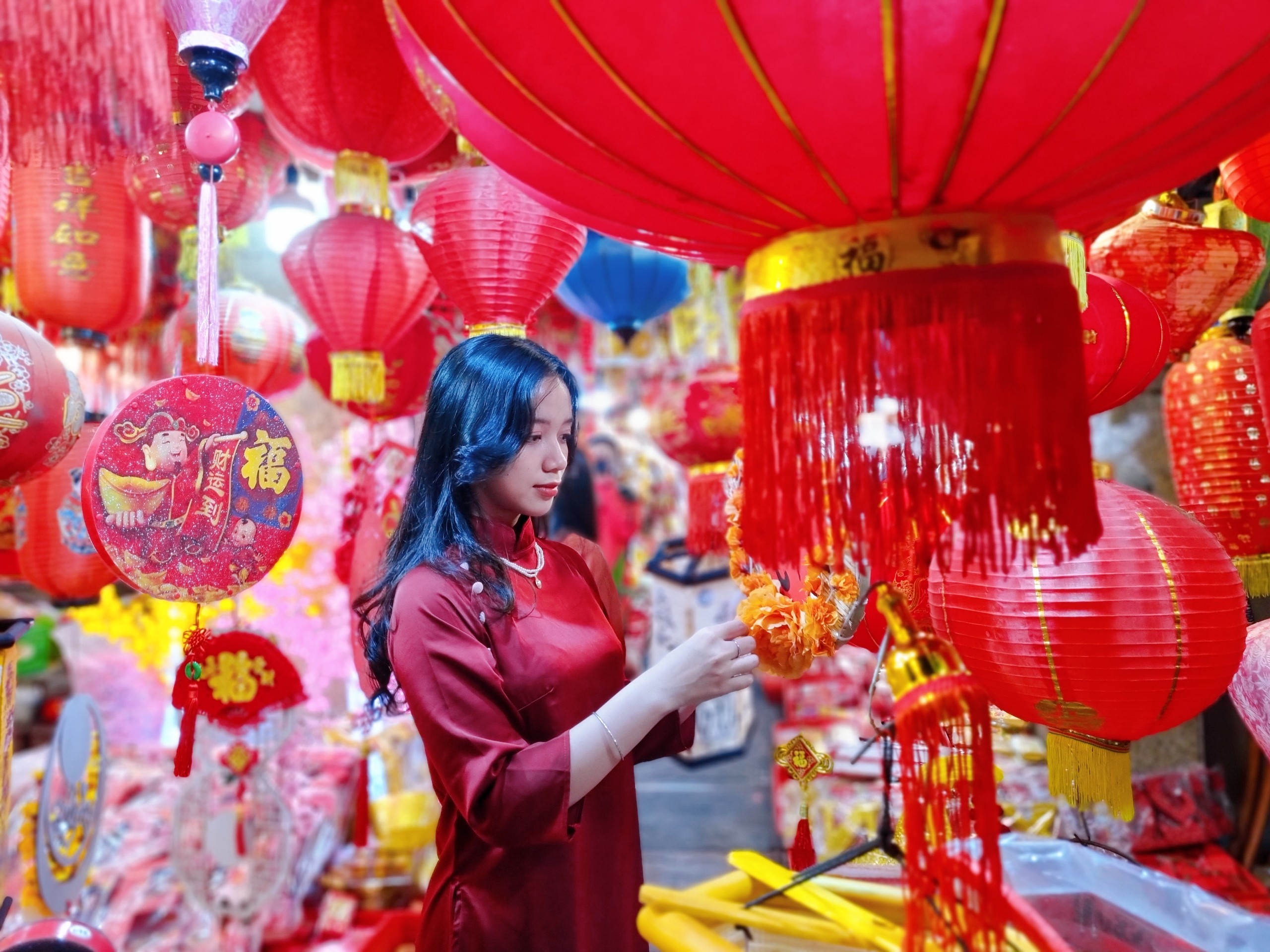 A woman poses beside Tet decorations at a store on Hai Thuong Lan Ong Street in District 5, Ho Chi Minh City. Photo: Nhat Xuan / Tuoi Tre