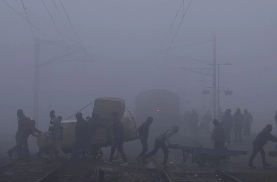 Labourers push cart as they cross railway tracks amidst heavy fog on a cold winter morning in New Delhi, India, January 9, 2023. Photo: Reuters