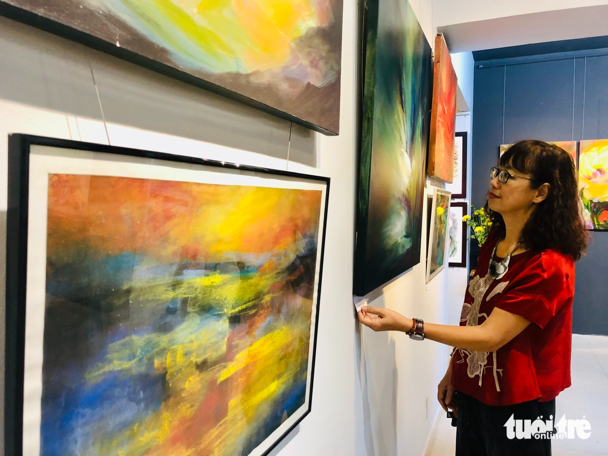 Painter Tran Thuy Linh looks at one of her spring-themed paintings, which are exhibited at the premises of the Ho Chi Minh City Fine Arts Association in District 3, Ho Chi Minh City, January 8, 2023. Photo: Hoai Phuong / Tuoi Tre