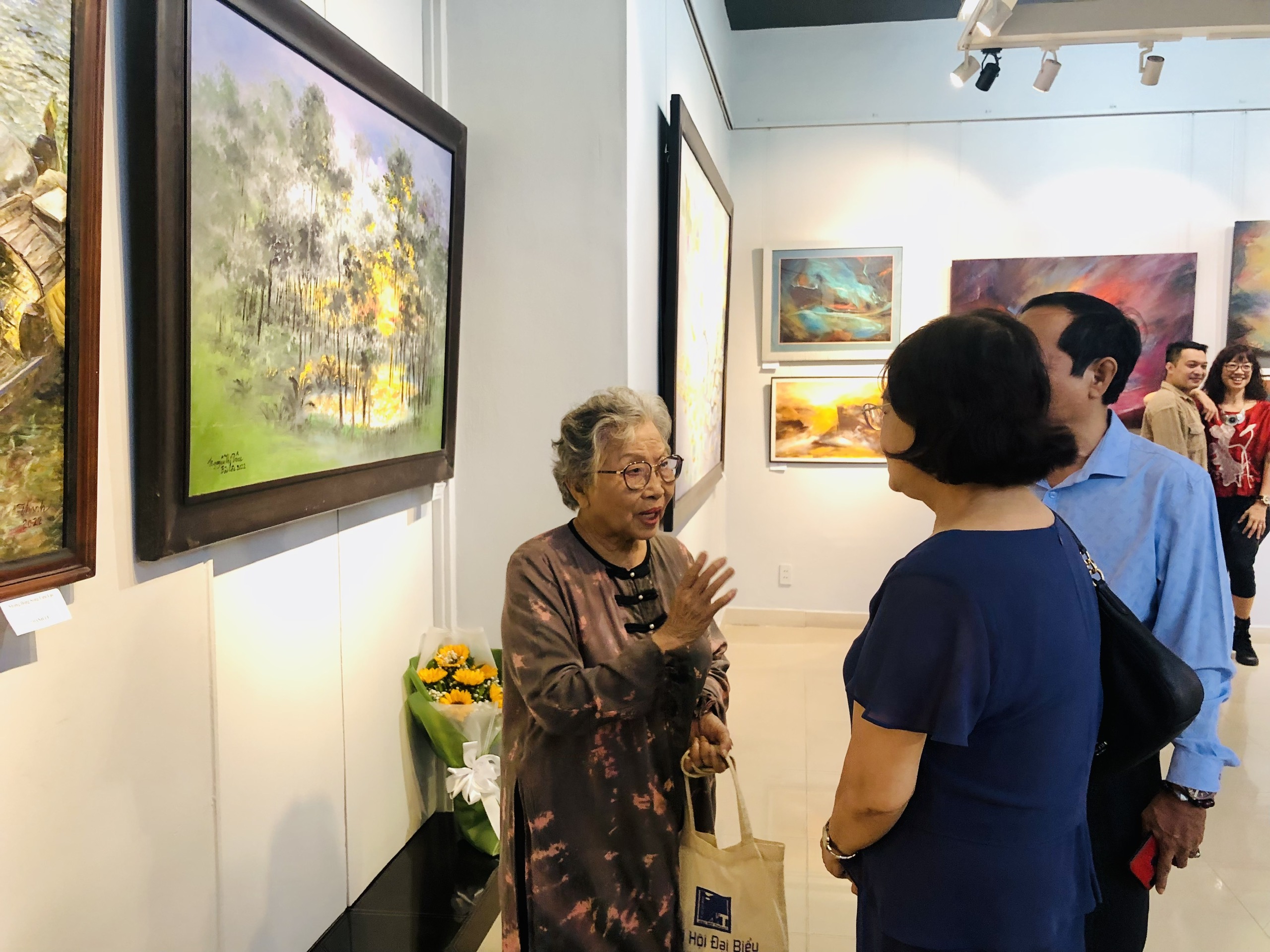 Painter Nguyen Thi Tam talks with visitors about her spring-themed paintings, which are on display at he premises of the Ho Chi Minh City Fine Arts Association in District 3, Ho Chi Minh City, January 8, 2023. Photo: Hoai Phuong / Tuoi Tre
