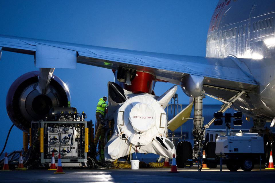 Technicians work on Virgin Orbit's LauncherOne rocket, attached to the wing of Cosmic Girl, a Boeing 747-400 aircraft, ahead of UK's First launch, at Spaceport Cornwall at Newquay Airport in Newquay, Britain, January 8, 2023. Photo: Reuters