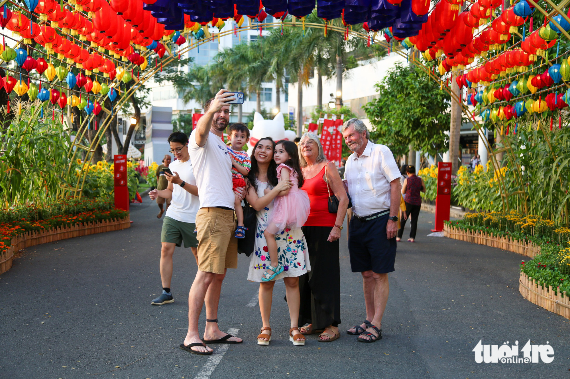 Hien, her husband, and her husband’s family members take photos on the flower road. Photo: Phuong Quyen / Tuoi Tre
