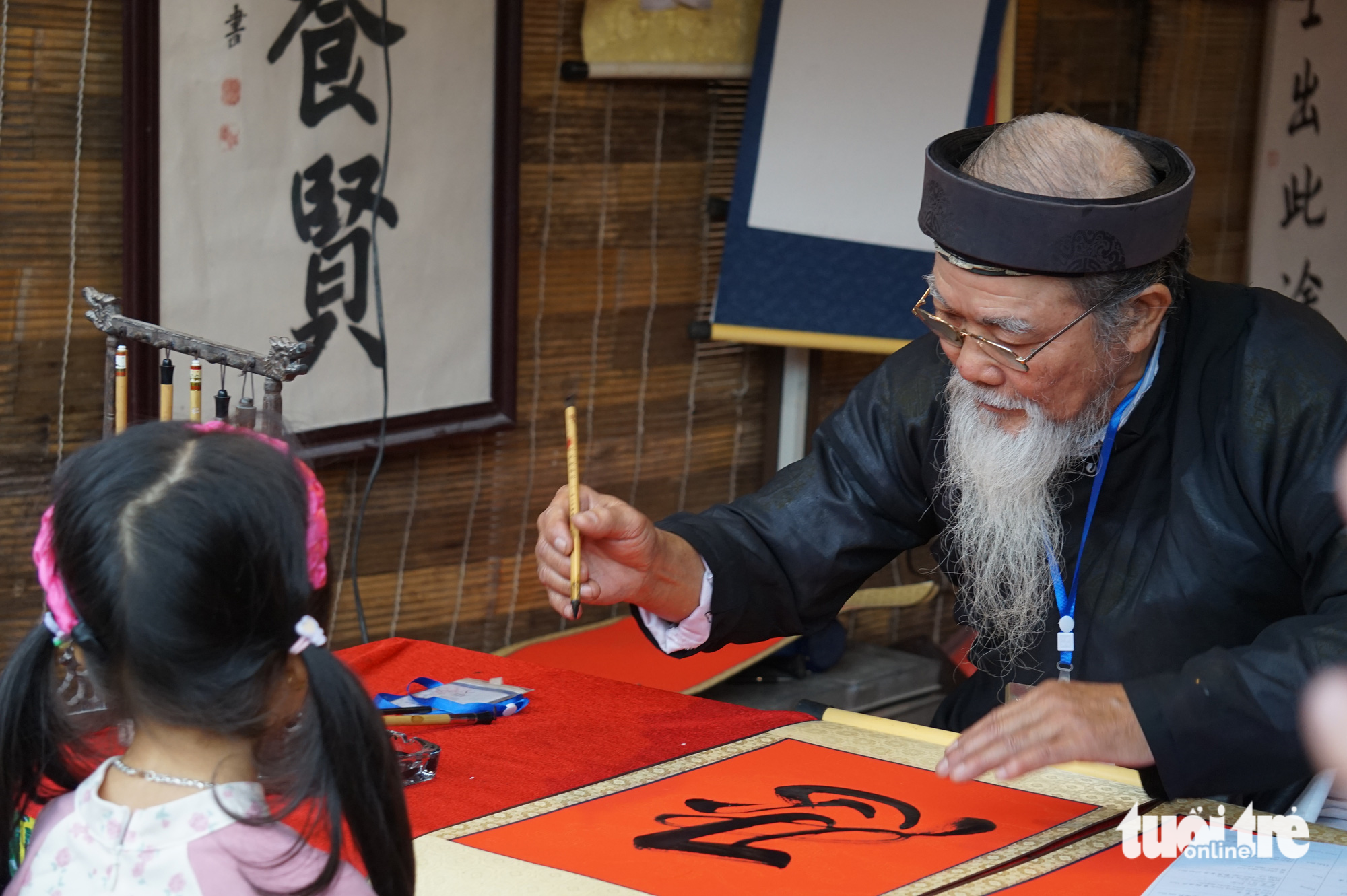 A girl waits an old calligrapher to give her a calligraphic work. Photo: T.Dieu / Tuoi Tre