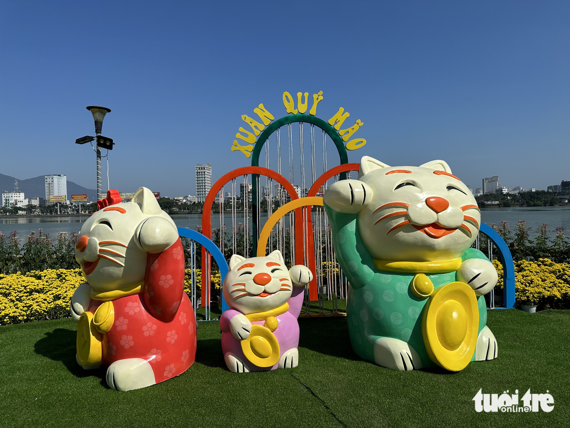 Statues of a cat family in traditional clothes with gold ingots on their hands. Photo: Moon Black / Tuoi Tre