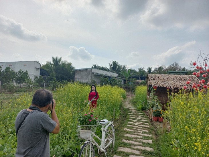 A woman in ‘ao dai’ (Vietnamese traditional dress) poses for a photo at the Tam Giac Mach Farm in Cai Rang District, Can Tho City, Vietnam’s Mekong Delta, on January 22, 2023. Photo: Lan Ngoc / Tuoi Tre