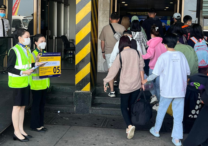 Ground service employees hold a board with flight information to facilitate passengers. Photo: Thanh Thanh / Tuoi Tre