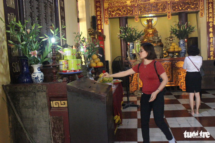 A woman is shown putting merit money into a box at Quan Su Pagoda in Hanoi, Vietnam. Photo: Thien Dieu/ Tuoi Tre